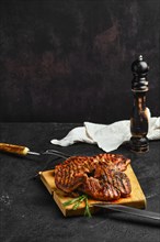 Juicy lamb steaks on wooden cutting board over black background