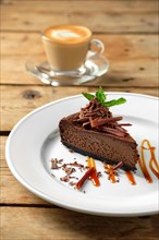 Piece of chocolate cake with cappuccino on wooden table
