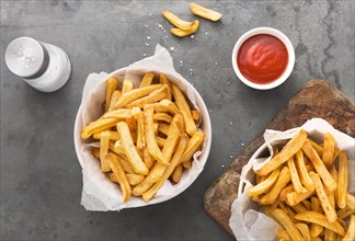Flat lay french fries with ketchup salt shaker