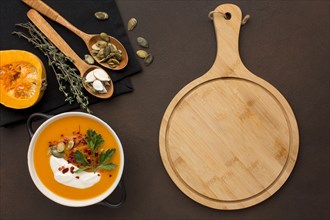 Flat lay of winter squash soup in bowl with chopping board and spoons