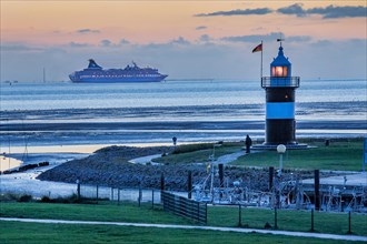 Sielhafen with lighthouse Kleiner Preusse and cruise ship Artania on the Weser at dusk