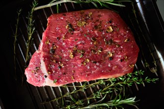 Top view of raw steak with spices on grilling pan