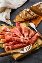 Rolled slices of jamon on wooden cutting board