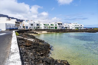 White buildings with blue and green windows by the ocean in Corralejo