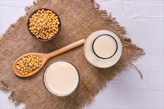 Top view of bottle of soy milk with soybeans on white table