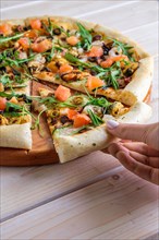 Hand picking slice of pizza with shrimps