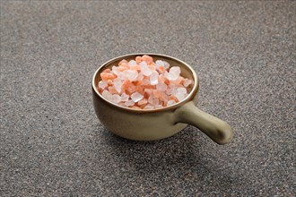 Pink Himalayan salt in a ceramic bowl on stone background