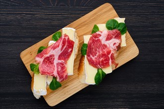 Overhead view of camembert sandwich with smoked bacon on dark wooden table