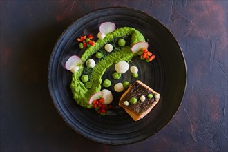 Fried salmon with pea mash decorated with radish and peas