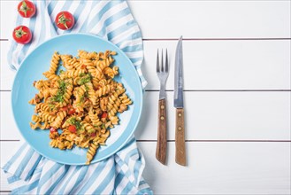 Pasta fusilli with tomato cutlery white wooden table