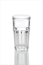 Empty transparent faceted glass with reflection on white background