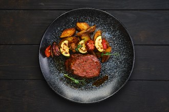 Top view of juicy beef steak with potato wedges and grilled vegetables on skewer