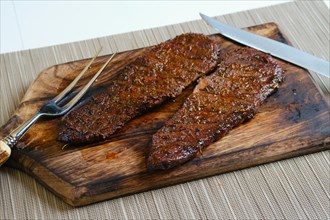 Juicy grilled top blade beefsteak on wooden cutting board