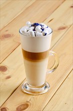 Latte macchiato in tall transparent glass on wooden background
