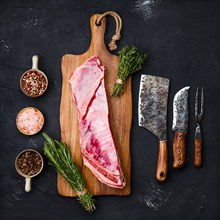 Fresh raw lamb breast and flap on wooden cutting board with herbs and seasoning