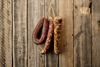 Assortment of dried meat and sausages hanging on a barn wall
