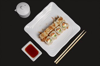 Top view of portion of bonito rolls served on plate with soy sauce and wooden chopsticks