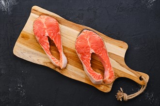 Raw fresh salmon steak on wooden cutting board
