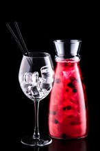 Jar with sangria with forrest berries and a wine glass isolated on black background