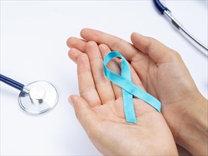 Close up hands holding blue ribbon with stethoscope