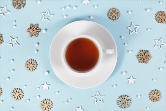 Cup of tea surrounded by seasonal winter decoration on blue background