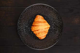Top view of freshly baked big croissant on a plate
