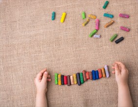 Toddlers hand putting crayons in line on canvas