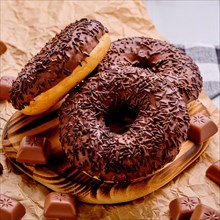 Closeup photo of chocolate donuts on wooden plate