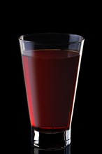 Glass of cranberry juice isolated on black background