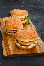 Homemade burger with chicken cutlet on long wooden board