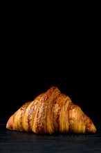 Fresh golden croissant on black table