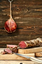 Smoked dried beef meat cut on slices on wooden cutting board