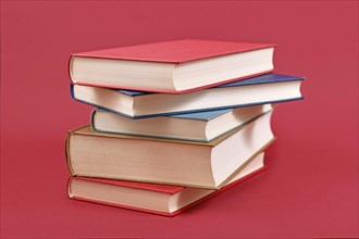 Stack of old hardcover books on dark red background