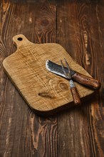 Rustic old cutting board with handmade forged knife and fork
