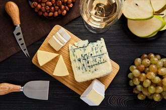 Top view of assortment of cheese and snack for wine on dark wooden table