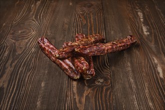 Dried jerked deer and pork sausage on wooden background