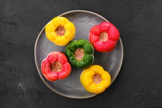 Top view of colorful bell pepper stuffed with meat and rice on black background