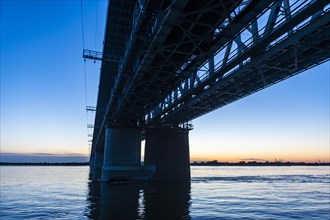 Giant bridge spanning over the Amur river at sunset