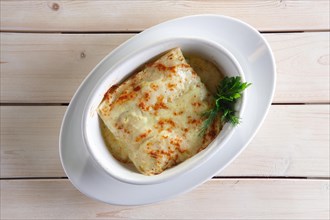 Thin pancakes with stuffing baked in oven with melted cheese