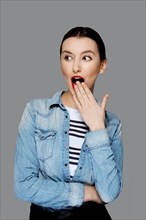 Pretty surprised fashion model in jeans shirt with tan makeup and red mat lips