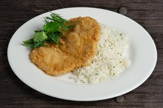 Chicken fillet in breading with rice on wooden table