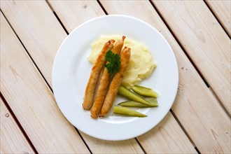 Fried sausage with mashed potato and pickled cucumber
