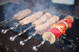 Pork meat and mushrooms on skewer over the charcoal in barbecue