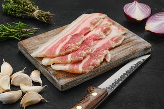 Slices of pork bacon on wooden cutting board