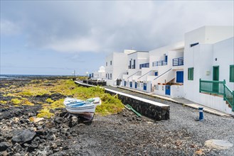 White buildings with blue and green windows by the ocean in Corralejo
