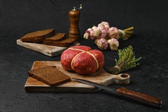 Smoked round beef sausage on cutting board over black background