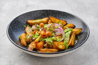 Fried potato wedges with champignons dressed with red and white onion