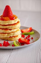 Stack of hot flapjacks served with fresh strawberries and kiwi