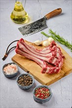 Overhead view of raw fresh doe ribs with spice and herb over concrete background