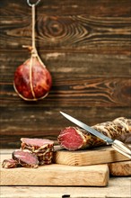 Smoked dried beef meat cut on slices on wooden cutting board